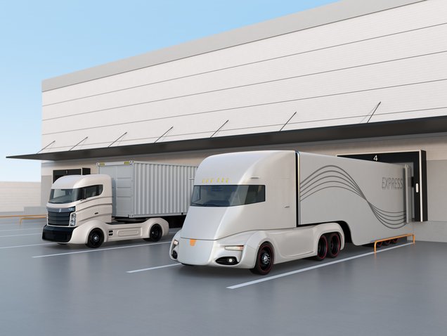 zwei Elektro-Lkw stehen jeweils an einer Laderampe